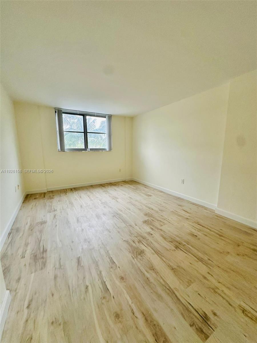 9273 Collins Avenue, Unit 207 Surfside, FL 33154 - Photo 9 of 14 an empty room with wooden floor and windows