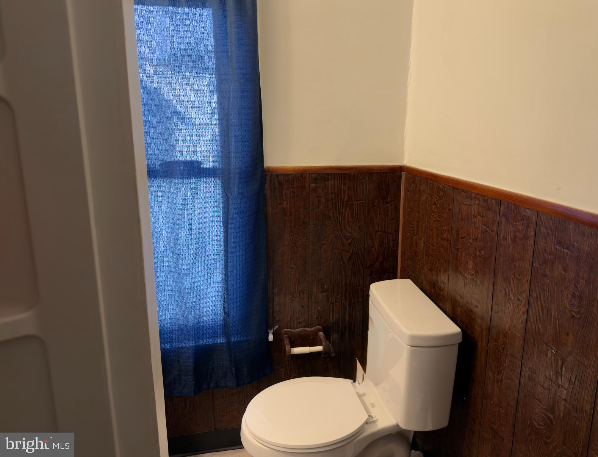 141 Hampton Street Bridgeton, NJ 08302 - Photo 15 of 18 a toilet sitting in a bathroom next to a wooden wall