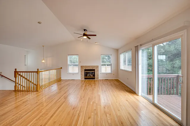 a view of an empty room with wooden floor fireplace and a window