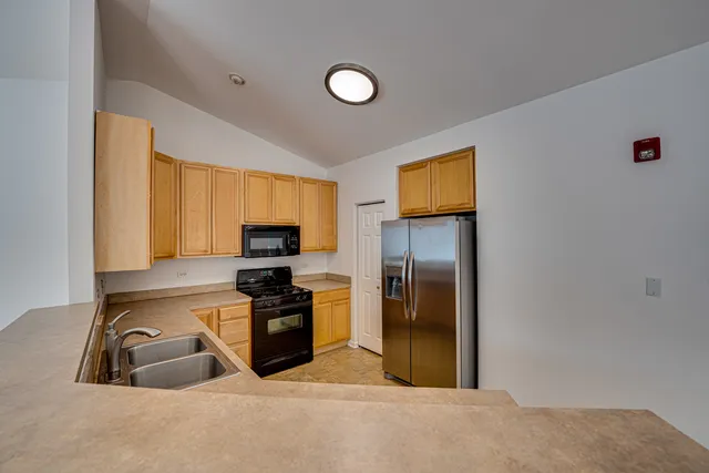a kitchen with granite countertop a refrigerator and a stove top oven