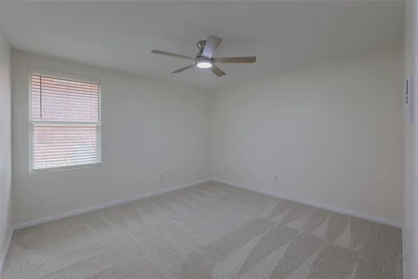 an empty room with a window and ceiling fan