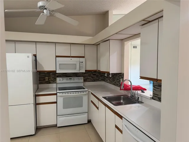 a kitchen with white cabinets and white appliances