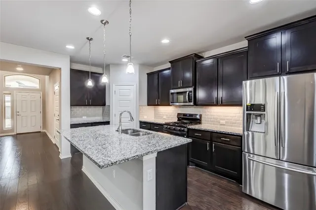 a kitchen with stainless steel appliances granite countertop a sink stove and refrigerator