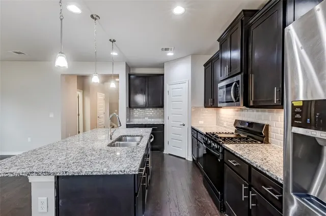 a kitchen with kitchen island granite countertop stainless steel appliances and wooden cabinets