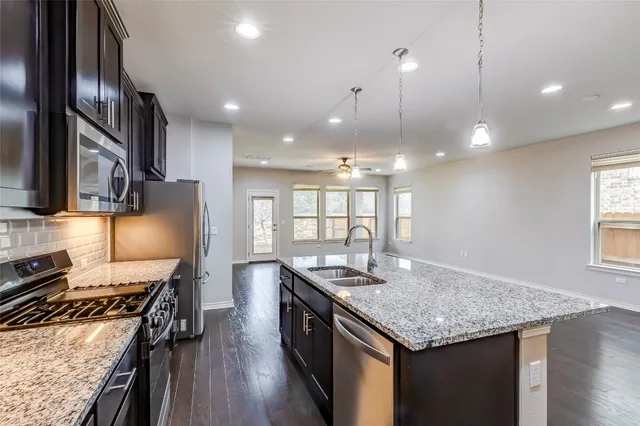 a large kitchen with granite countertop counter space a sink stainless steel appliances and cabinets