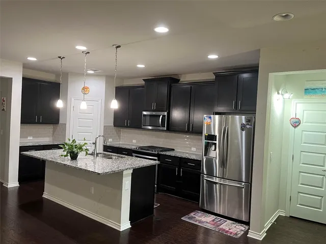 a kitchen with stainless steel appliances granite countertop a refrigerator a sink and a stove