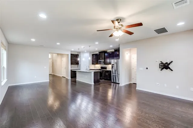 a view of an empty room with kitchen and window