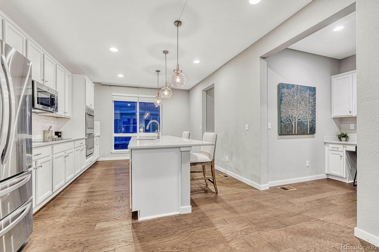 8338 Rivulet Point Highlands Ranch, CO 80129 - Photo 18 of 46 a kitchen with stainless steel appliances kitchen island granite countertop a refrigerator and a stove top oven