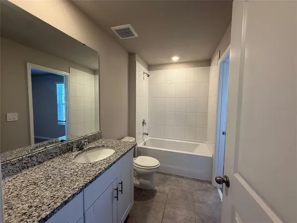 a bathroom with a granite countertop sink toilet mirror and bathtub