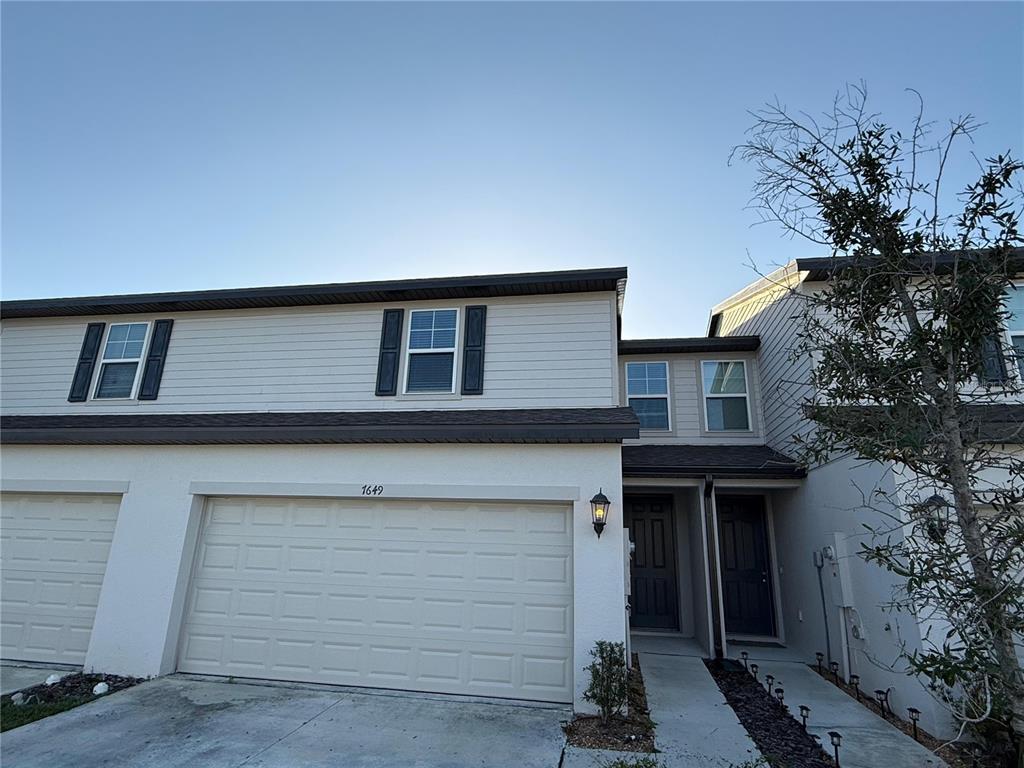 7649 Intrepid Road Wesley Chapel, FL 33545 - Photo 2 of 46 a front view of a house with a garden