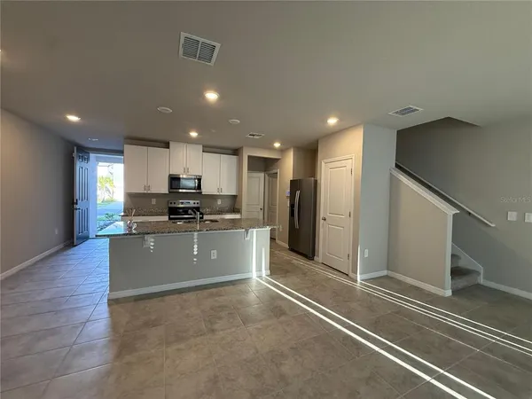 a large kitchen with stainless steel appliances kitchen island granite countertop a refrigerator and a stove top oven