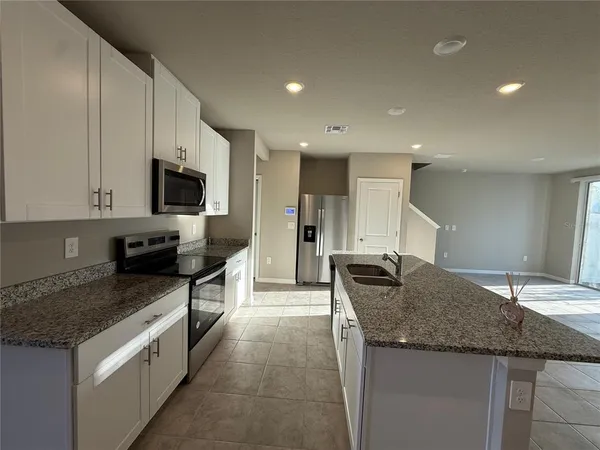 a kitchen with granite countertop a sink and white cabinets