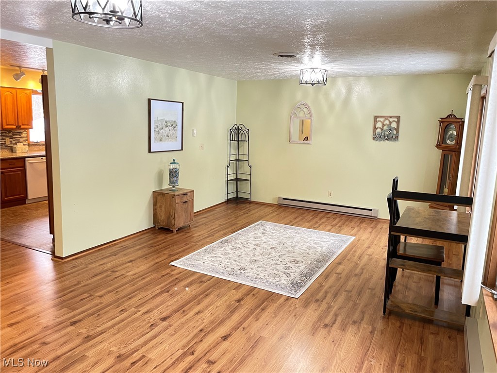 1381 Robb Road Conneaut, OH 44030 - Photo 8 of 50 Dining space with a textured ceiling, light wood finished floors, a baseboard heating unit, and a chandelier