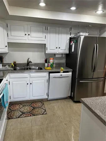 a kitchen with stainless steel appliances granite countertop a sink stove refrigerator and cabinets