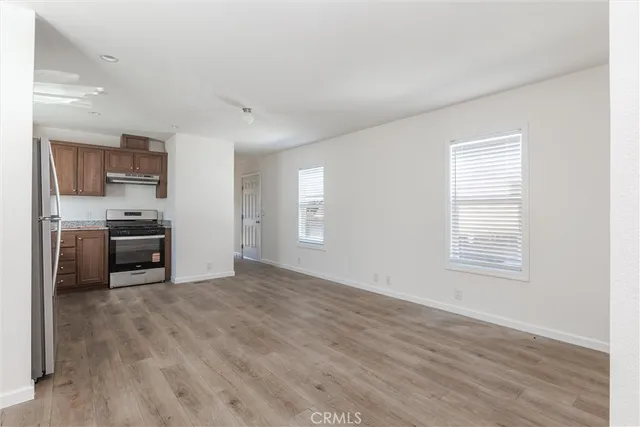 a view of a kitchen with wooden floor electronic appliances and windows