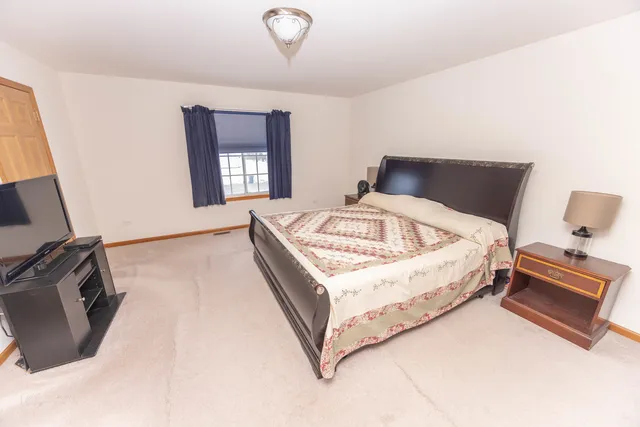 a bed sitting in a bedroom next to a window with wooden floor