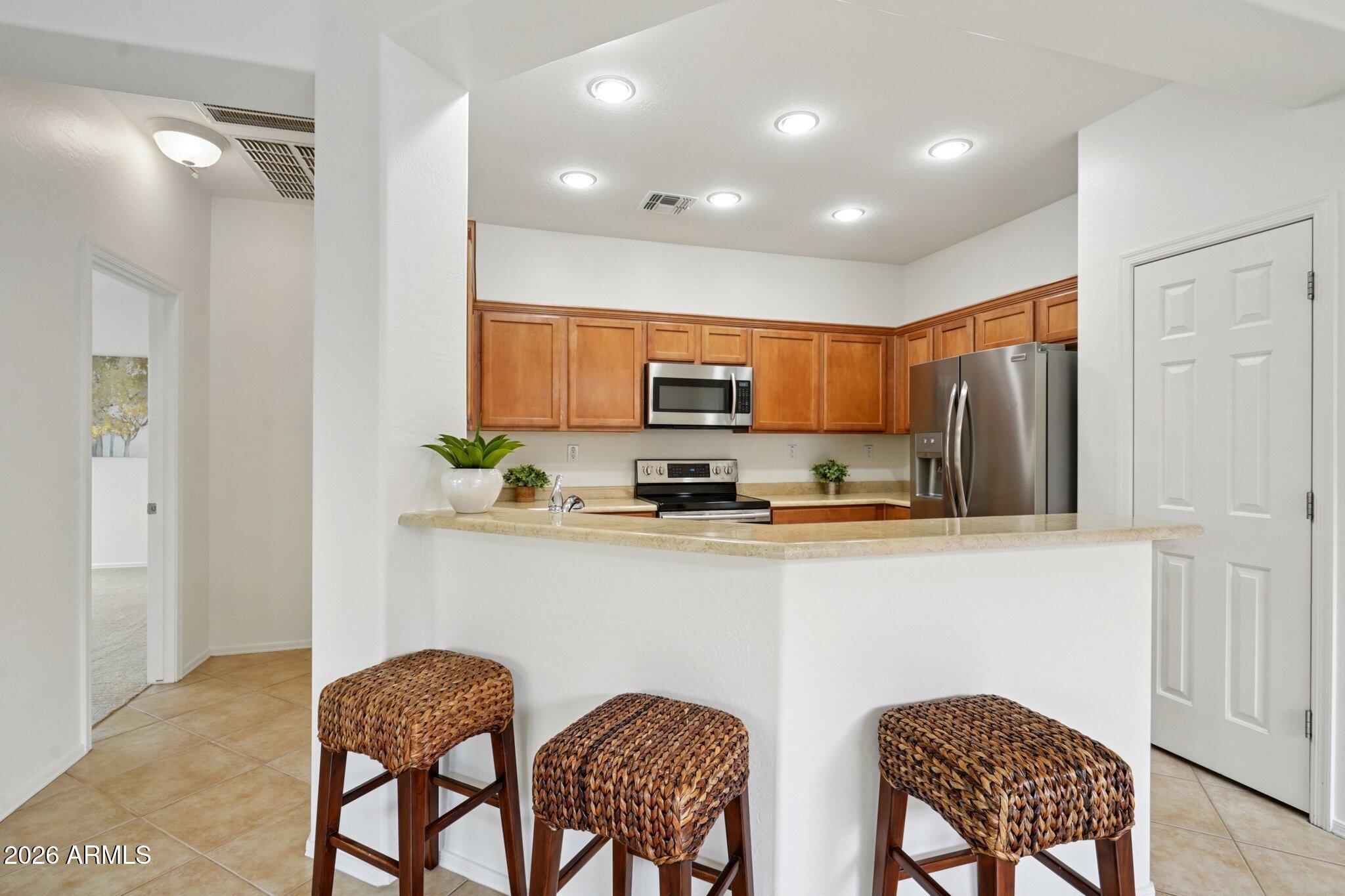 3852 West Ranier Court Anthem, AZ 85086 - Photo 9 of 58 a kitchen with stainless steel appliances granite countertop a dining table chairs refrigerator and microwave
