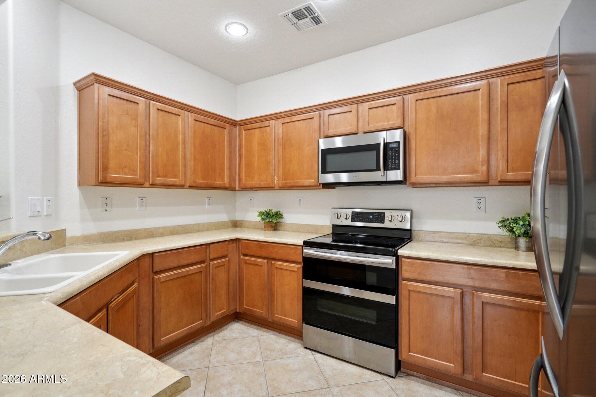 3852 West Ranier Court Anthem, AZ 85086 - Photo 10 of 58 a kitchen with stainless steel appliances granite countertop a sink stove and microwave