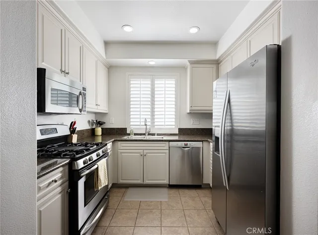 a kitchen with stainless steel appliances granite countertop a refrigerator a sink a stove a washer dryer and a cabinets