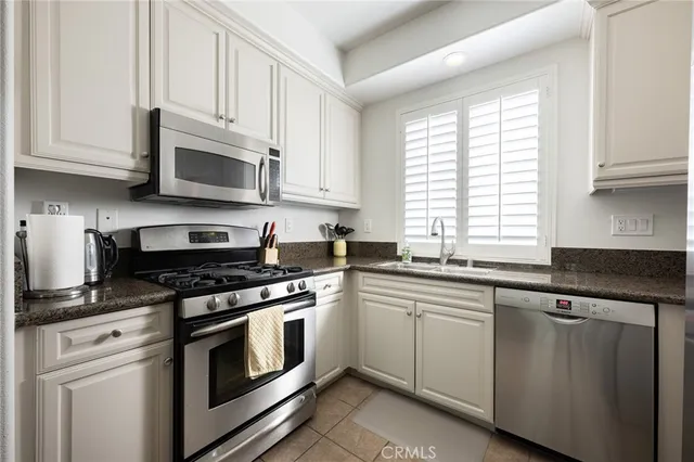 a kitchen with stainless steel appliances granite countertop white cabinets a sink and a stove