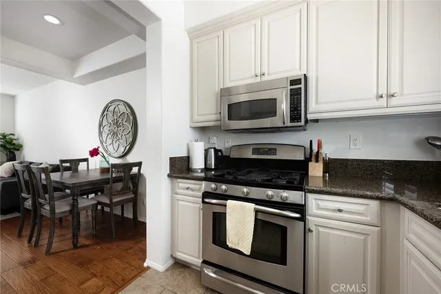 a kitchen with granite countertop a stove a microwave a dining table and chairs