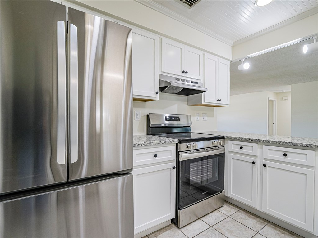 1331 Barber Street Sebastian, FL 32958 - Photo 11 of 32 a kitchen with stainless steel appliances granite countertop a refrigerator a stove and white cabinets