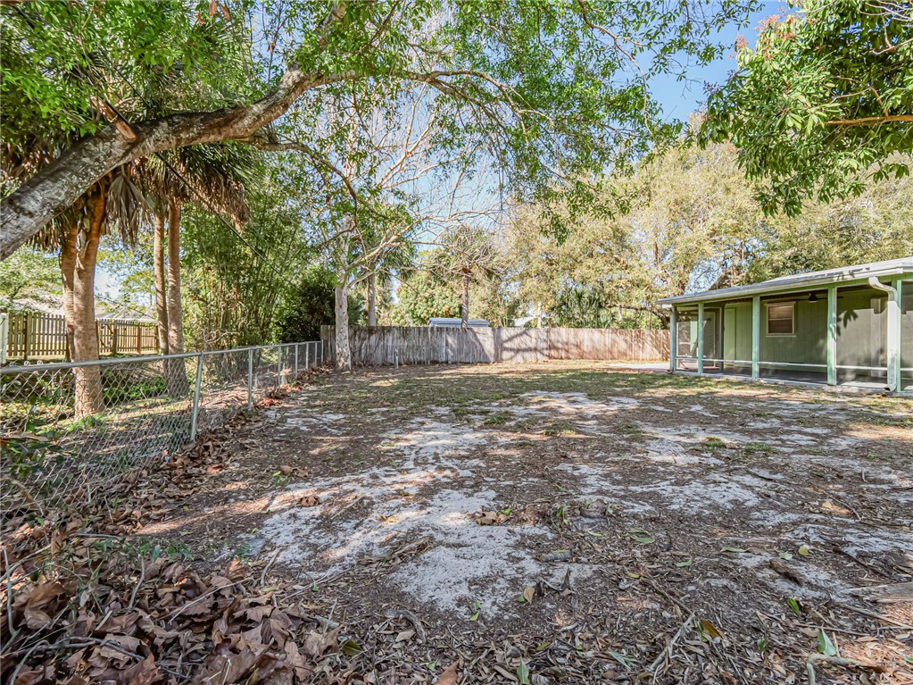 1331 Barber Street Sebastian, FL 32958 - Photo 30 of 32 a backyard of a house with large trees and outdoor seating