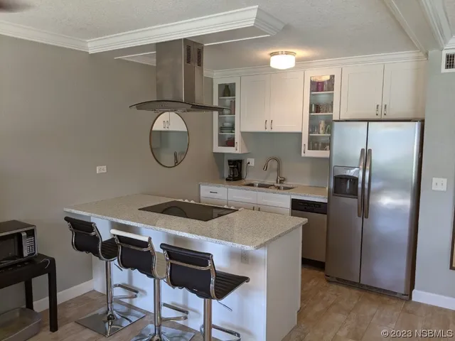 a kitchen with stainless steel appliances granite countertop a refrigerator a sink a stove and white cabinets