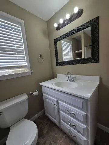 a bathroom with a granite countertop toilet sink and mirror