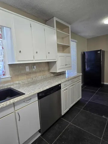 a kitchen with granite countertop white cabinets and stainless steel appliances