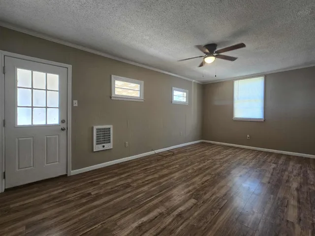 a view of an empty room with a window and wooden floor