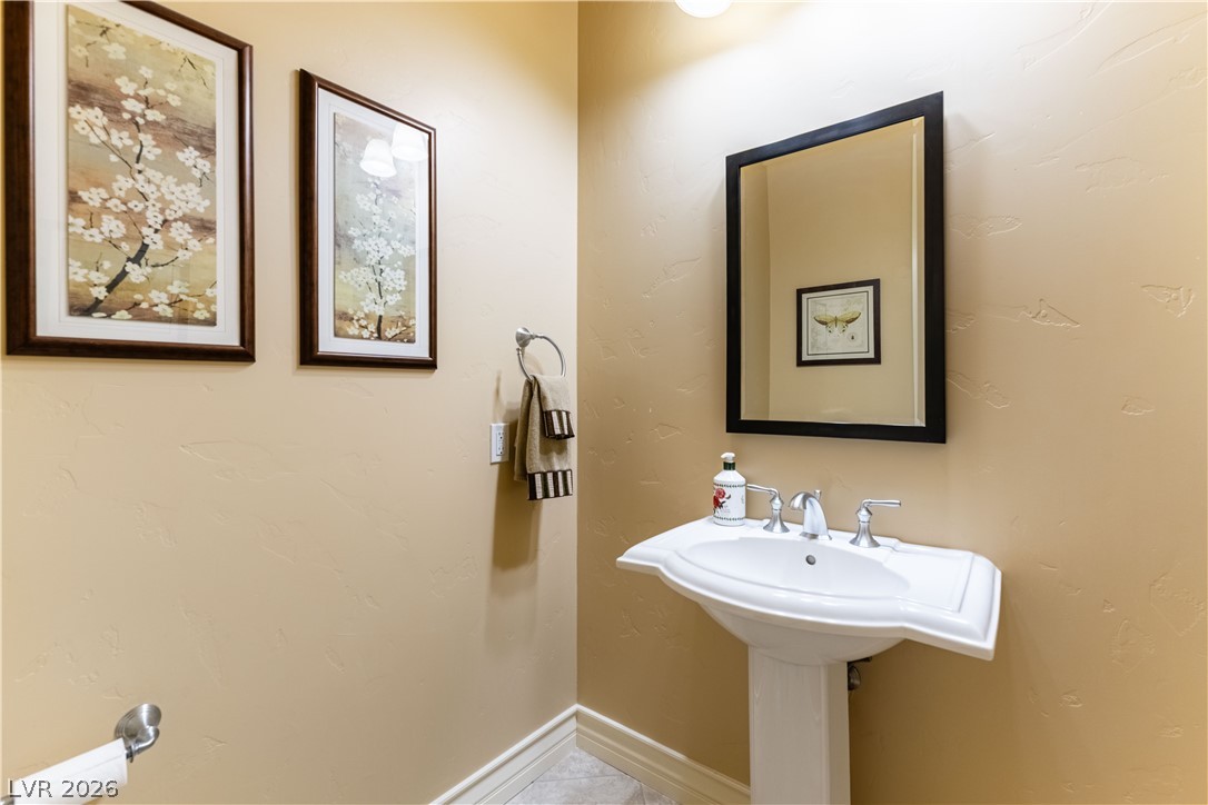 3661 Riley Ann Avenue Las Vegas, NV 89139 - Photo 19 of 42 A pristine pedestal sink and sleek framed mirror create a refreshing bathroom ambiance.