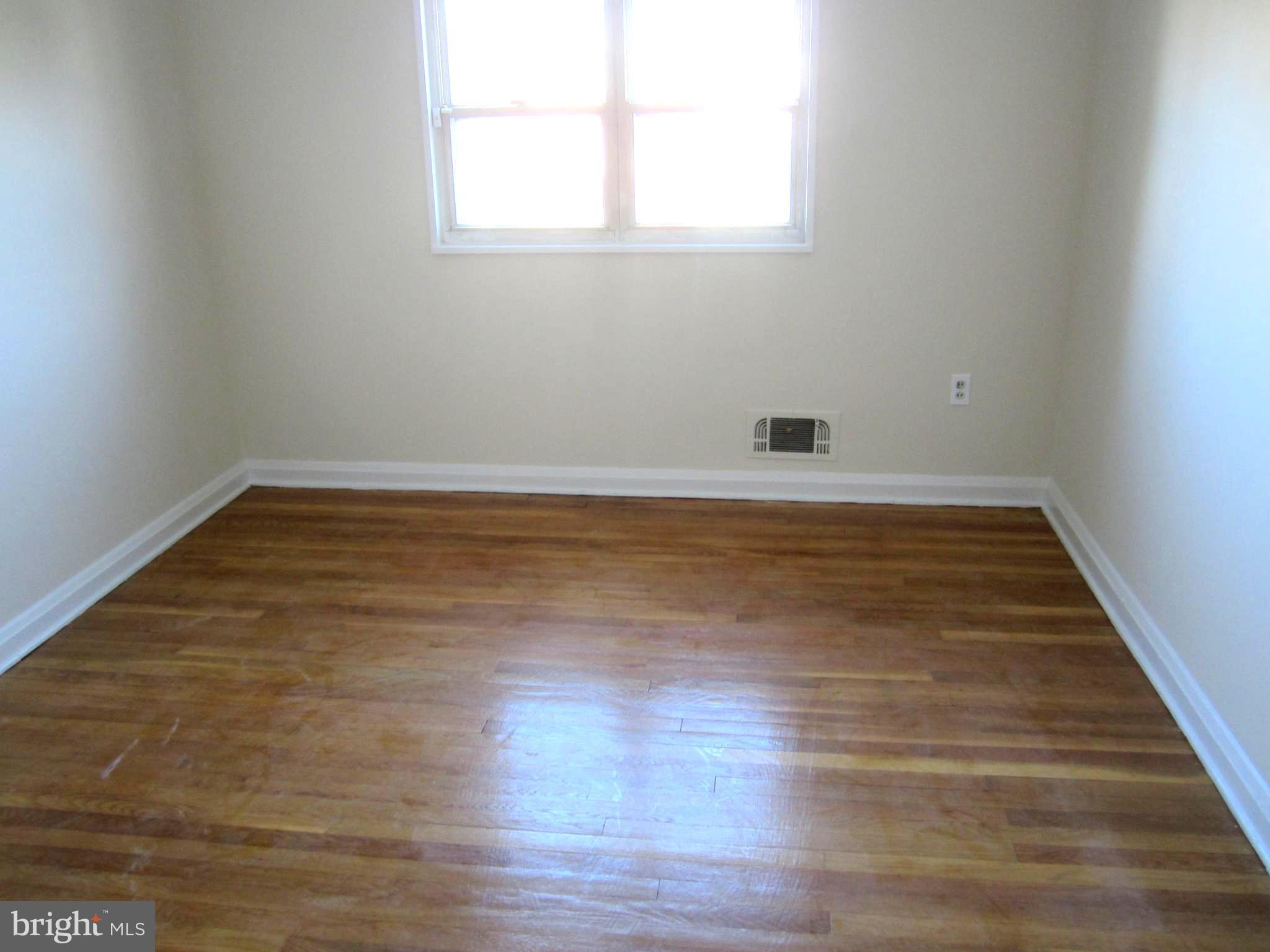 642 Brisbane Road Baltimore, MD 21229 - Photo 8 of 16 an empty room with wooden floor and windows