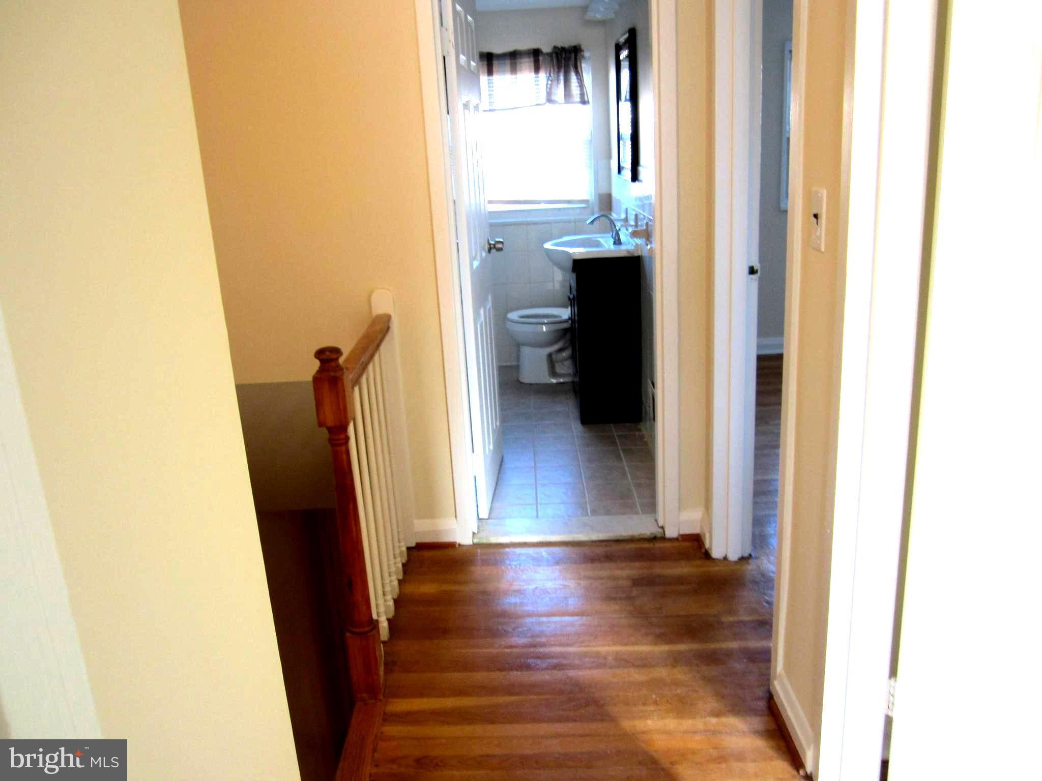 642 Brisbane Road Baltimore, MD 21229 - Photo 9 of 16 a view of a hallway with wooden floor and a bathroom