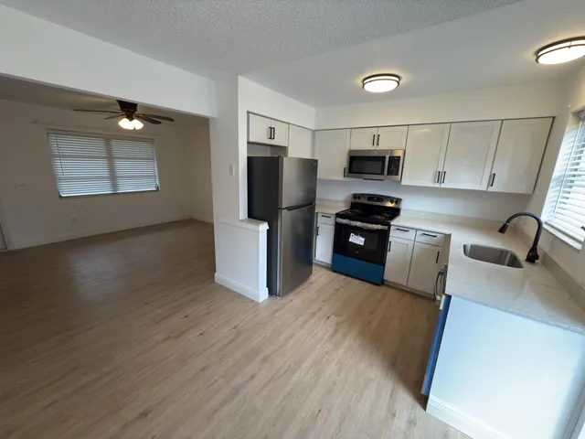 a kitchen with granite countertop a refrigerator and a stove top oven
