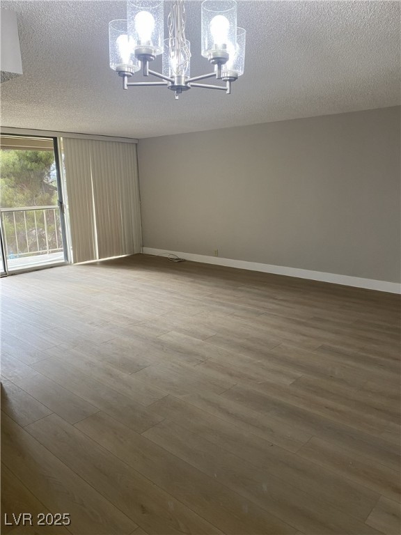 750 South Royal Crest Circle, Unit 342 Las Vegas, NV 89169 - Photo 8 of 21 Empty room featuring a textured ceiling, light wood finished floors, and a chandelier