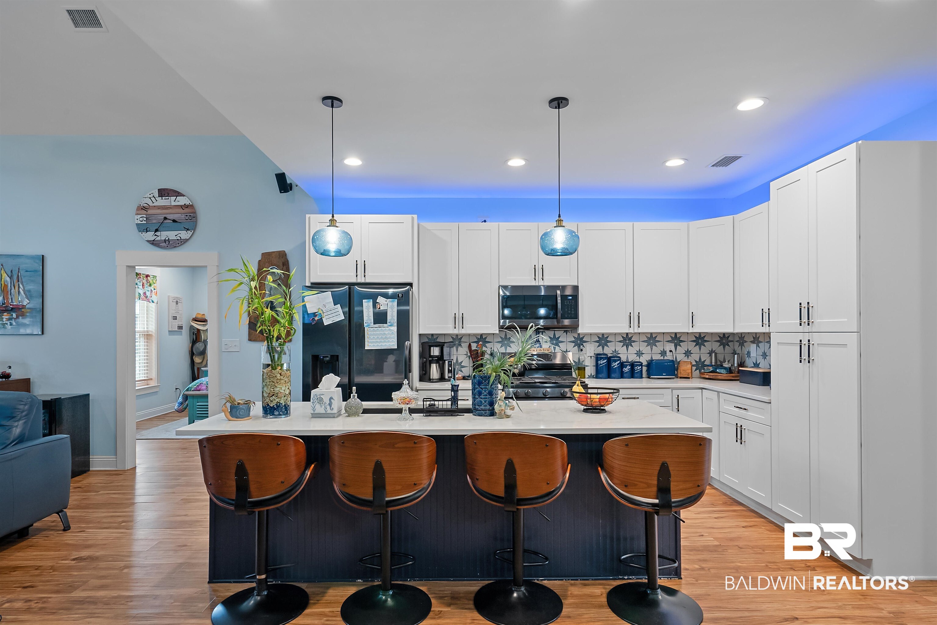 7266 Franklin Road Foley, AL 36535 - Photo 12 of 64 Modern kitchen featuring white shaker cabinetry, patterned tile backsplash, dark kitchen island with seating, pendant lighting, and wood-finish flooring