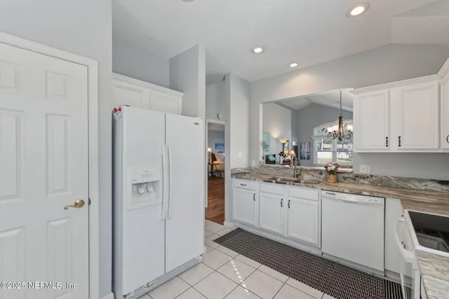 a kitchen with granite countertop a refrigerator sink and cabinets