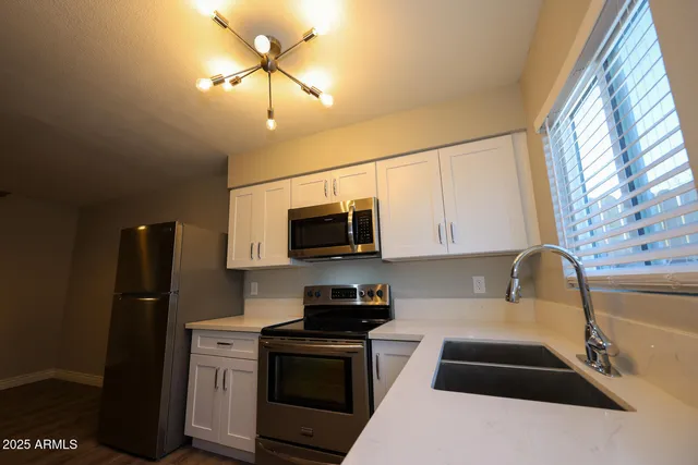 a kitchen with stainless steel appliances granite countertop a refrigerator a stove a sink and a microwave