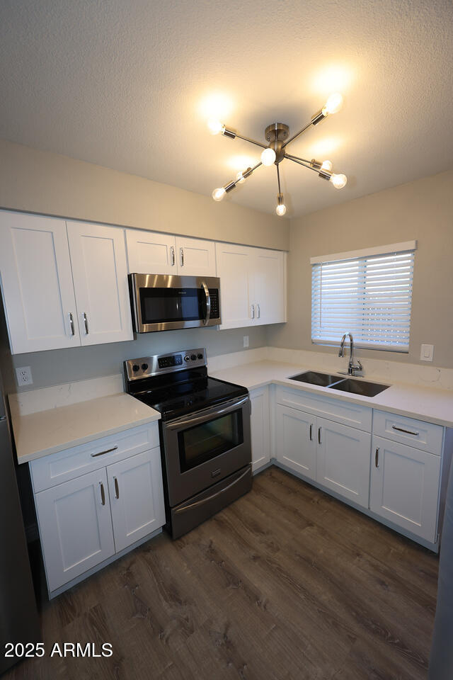 127 South Outpost Road, Unit 2 Apache Junction, AZ 85119 - Photo 4 of 14 a kitchen with granite countertop a stove a sink and white cabinets