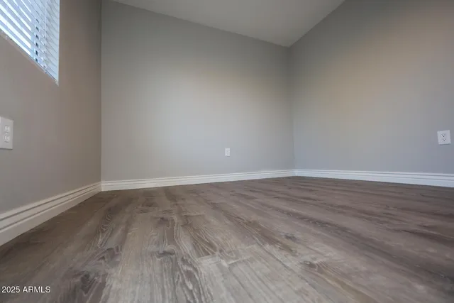 an empty room with wooden floor and fan