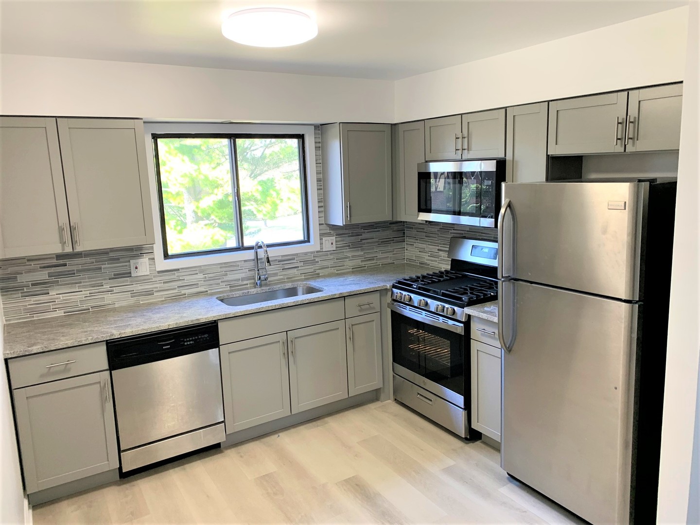 1741 Harrow Court, Unit B Wheaton, IL 60189 - Photo 13 of 24 a kitchen with white cabinets stainless steel appliances a sink and a window