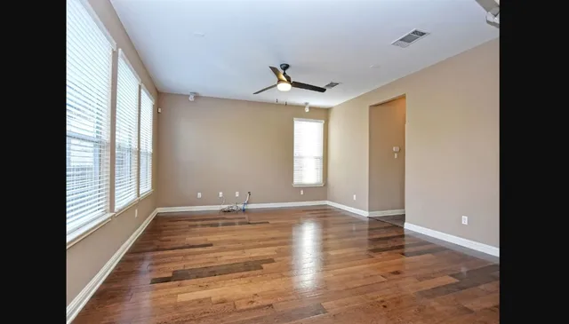 a view of empty room with wooden floor and fan