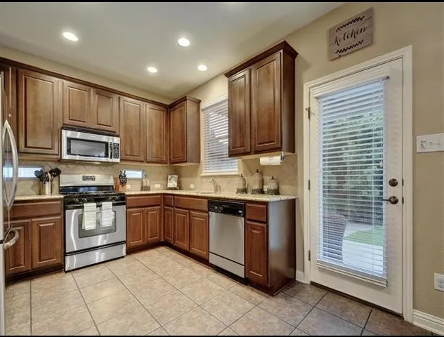 a kitchen with stainless steel appliances granite countertop a stove top oven a sink dishwasher and a refrigerator