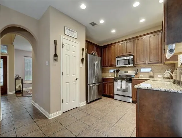 a kitchen with granite countertop a refrigerator and a stove top oven