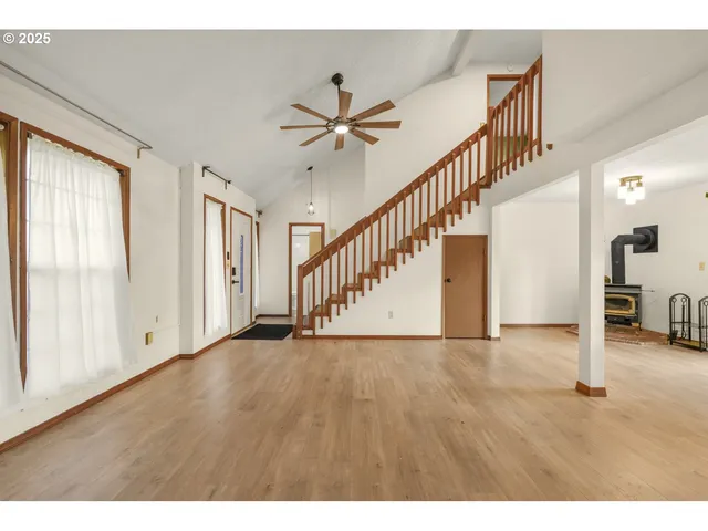 a view of an empty room with wooden floor and a ceiling fan
