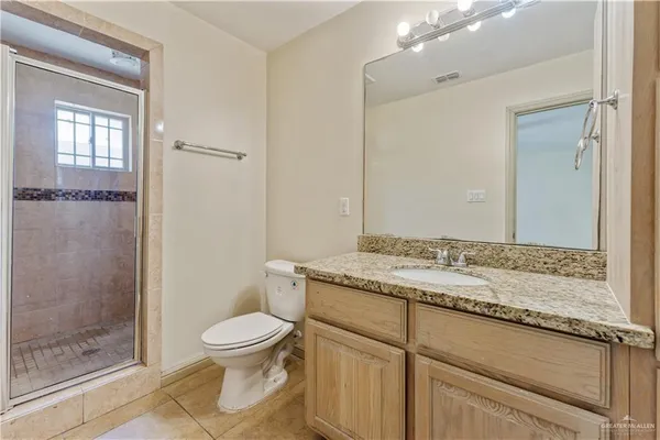 a bathroom with a granite countertop sink a toilet and shower