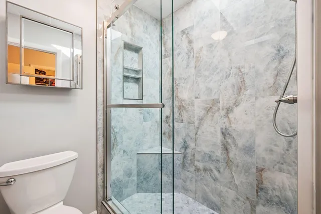 a bathroom with a granite countertop shower and a toilet