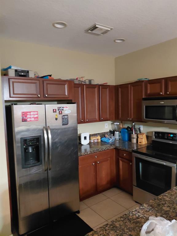 21205 Northwest 14th Place, Unit 319 Miami, FL 33169 - Photo 3 of 14 a kitchen with stainless steel appliances granite countertop a stove a sink and a refrigerator