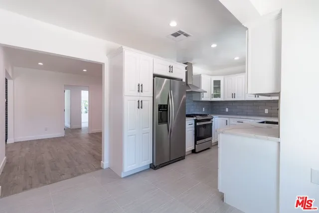 a kitchen with stainless steel appliances granite countertop a refrigerator sink and stove